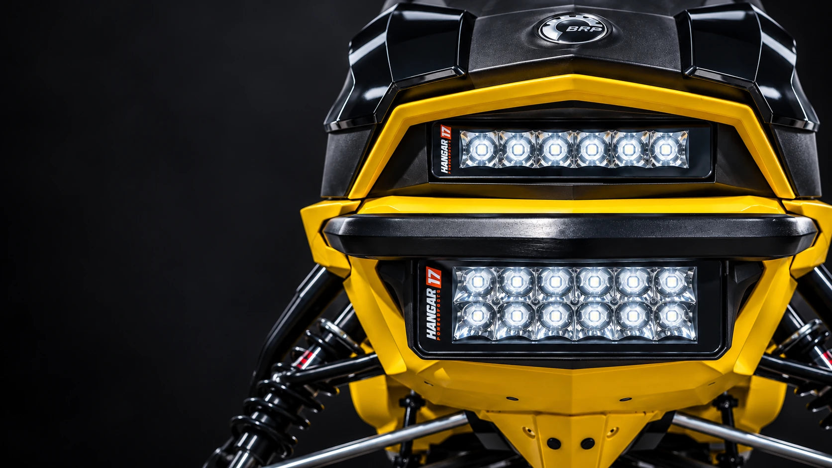 Upper and lower Hangar 17 Spot Pro light bars installed on a yellow snowmobile against a black studio background